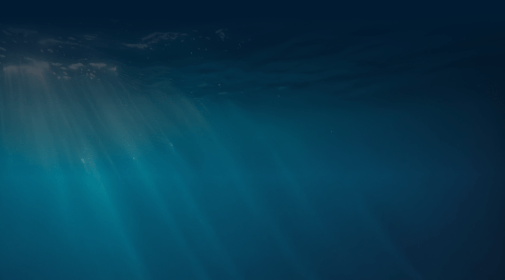 Sunlight beams through clear blue ocean water creating a serene, underwater scene.